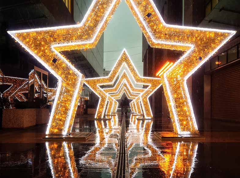 illuminated electric light stars in the rain reflecting prettily on a rainy pavement