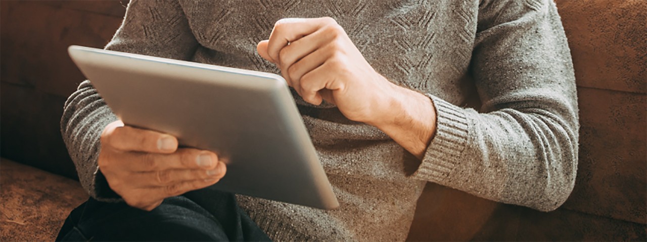 torso view of person sitting on a sofa holding a tablet