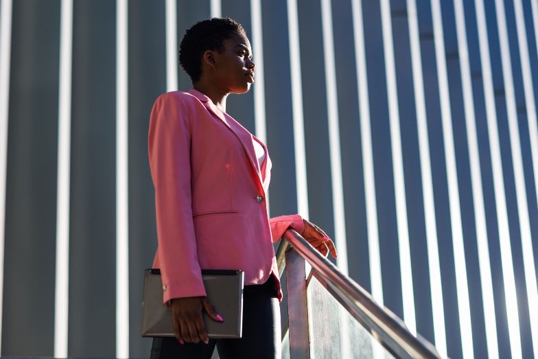 young professional wearing pink blazer standing at the top of an outdoor staircase