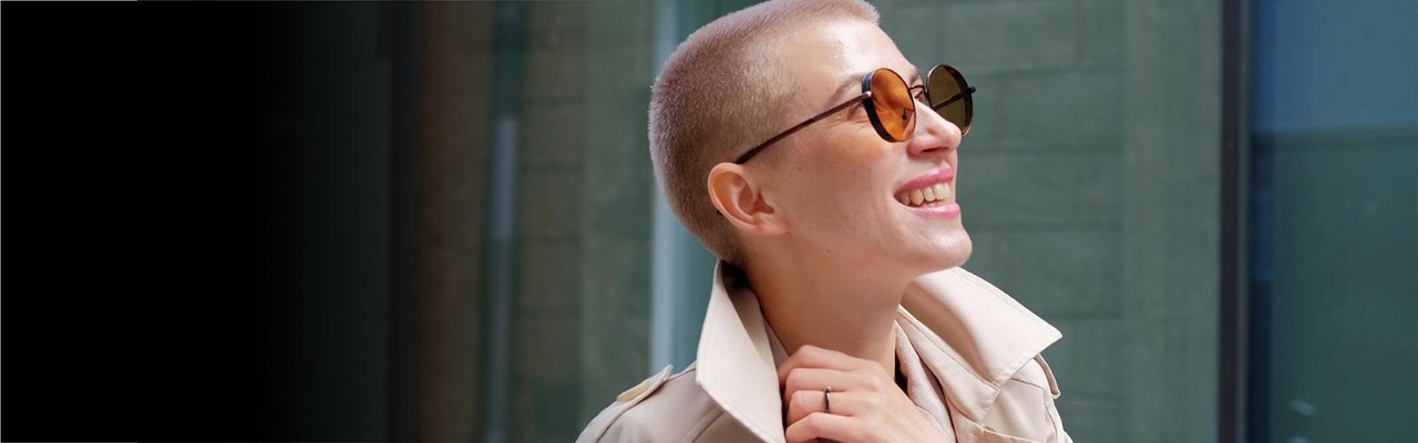 Happy young person wearing trendy sunglasses walking along street Happy young person wearing trendy sunglasses walking along street
