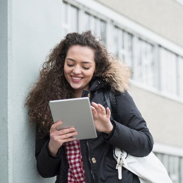 Happy student outside school building using tablet