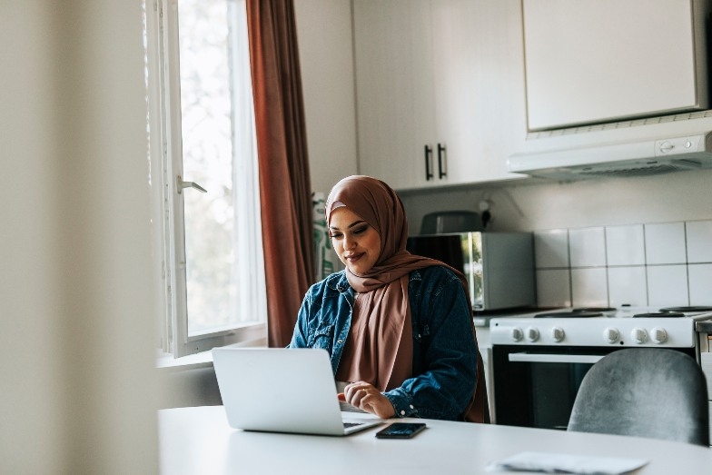 young person studying on laptop in kitchen