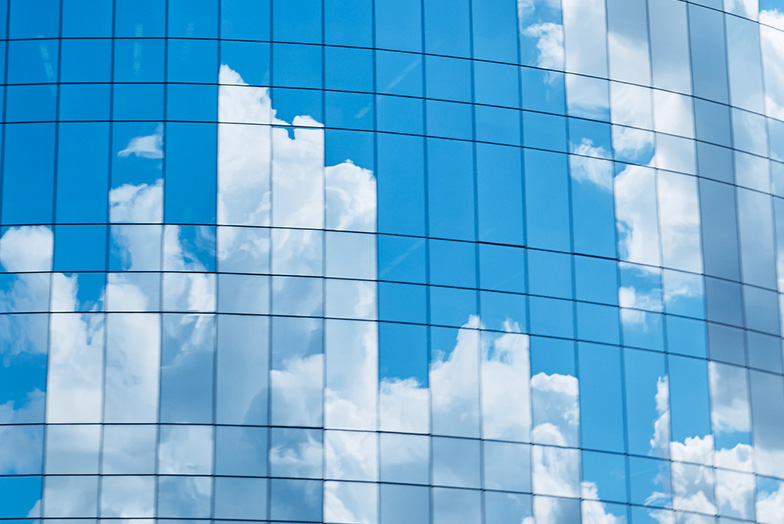 A blue sky and clouds reflected onto the windows of a building