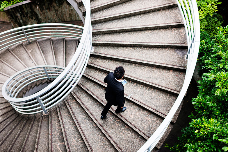 A person walking up an outdoor spiral staircase