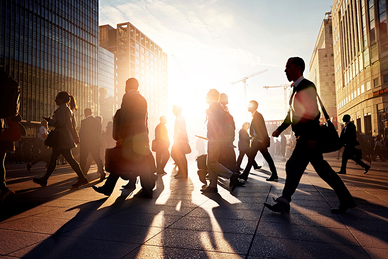 Sun casting shadows on a busy street of business people walking