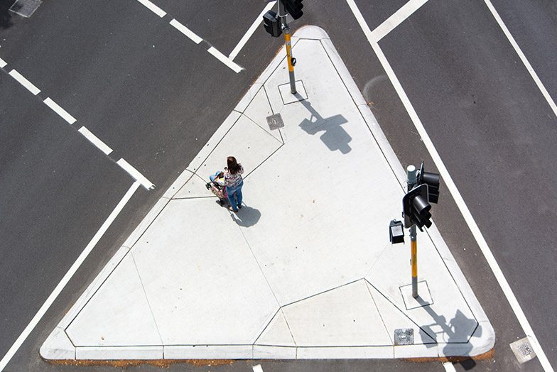 Person with a pushchair at a triangular road crossing for pedestrians