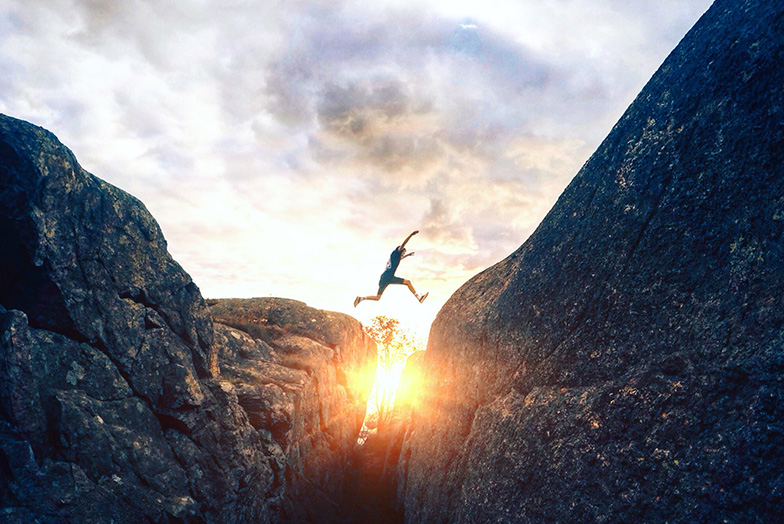 Person jumping between rocks