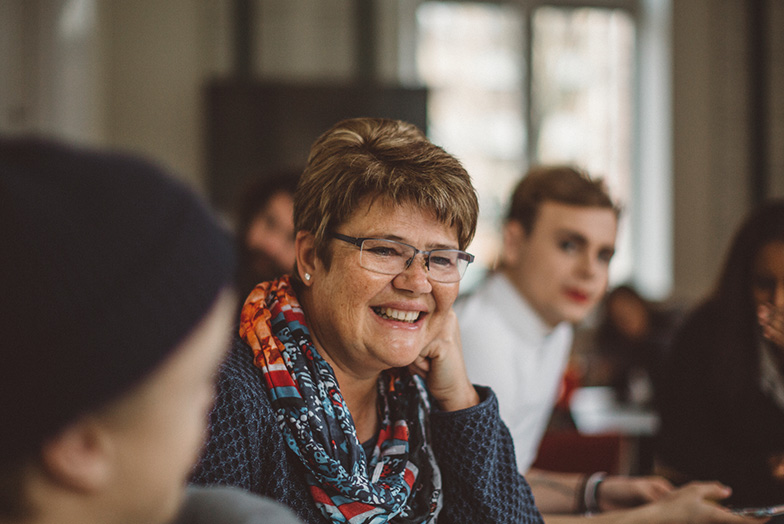 Smiling person sat wearing glasses and a colourful scarf 