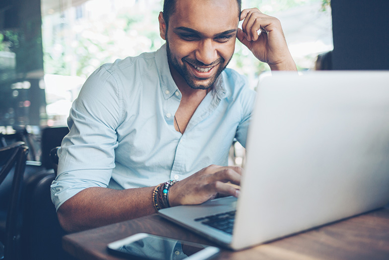 Person sat smiling at an open laptop
