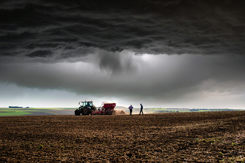 Two persons in a field with tractor 