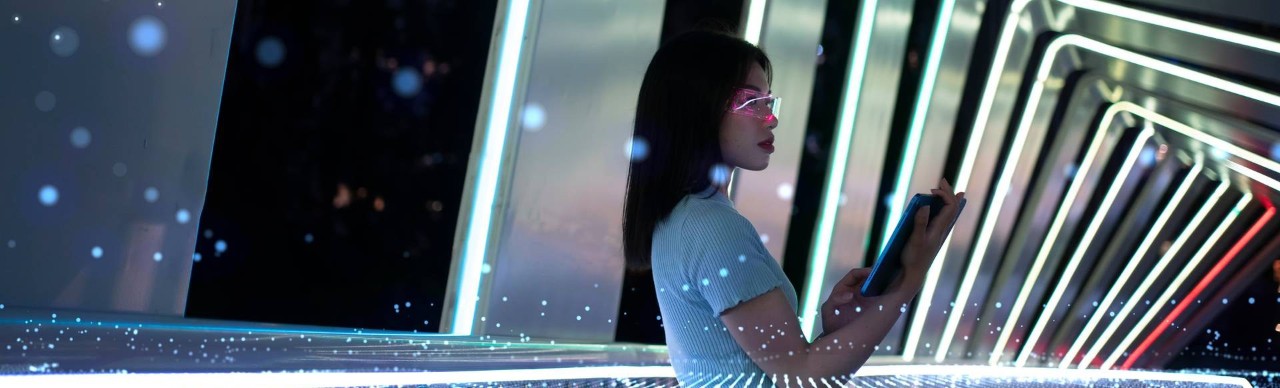 Person holding tablet looking out over a modern bridge with illuminated digital lights overlaid