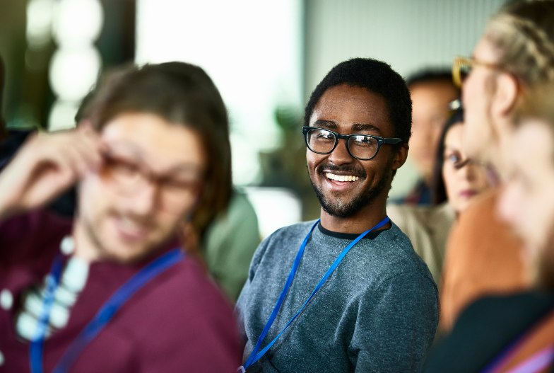 smiling person wearing glasses and lanyard in classroom