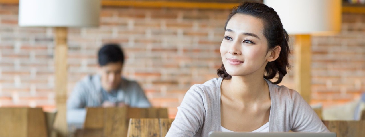 young person working on laptop in cafe