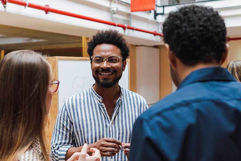 person standing with two others while talking in an office