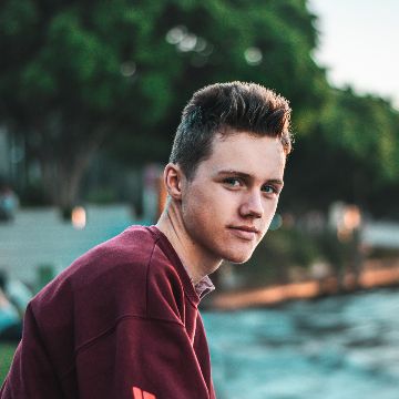 young person wearing beanie hat and headphones smiling skywards 