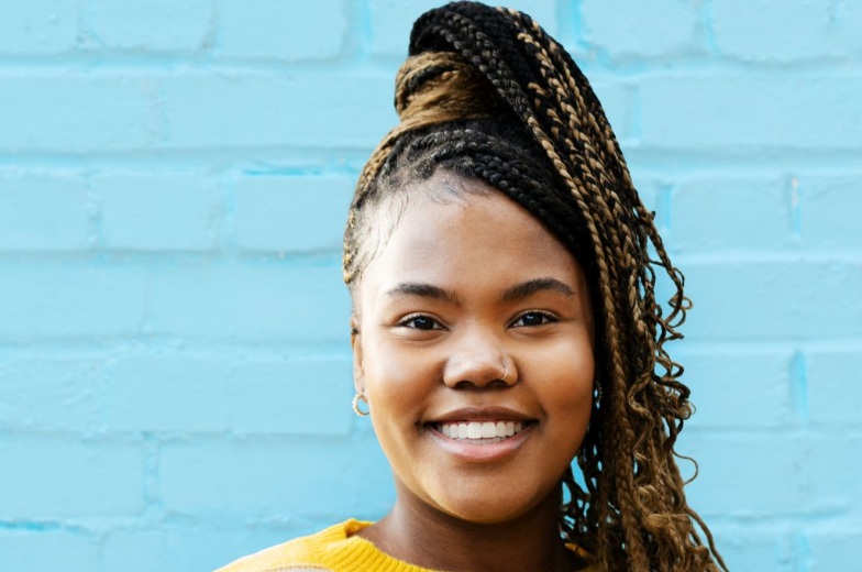 young happy person smiling to camera in front of a bright blue wall