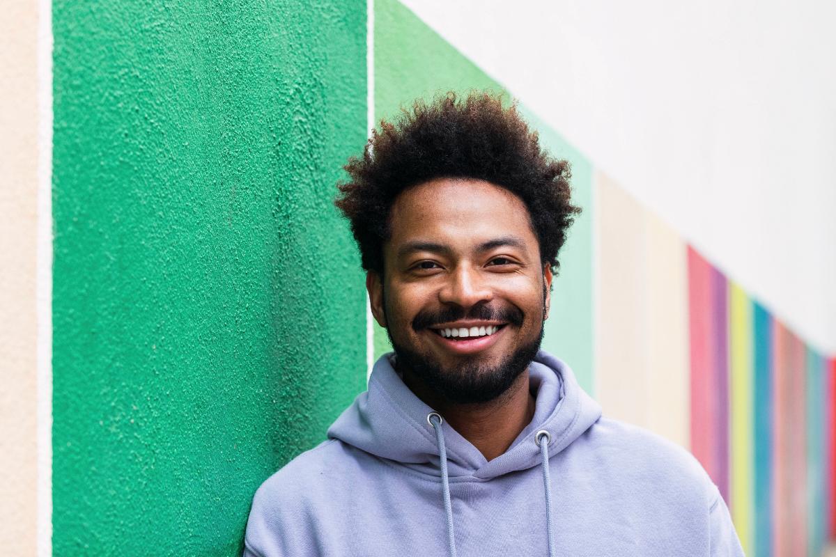 happy person smiling to camera in front of brightly painted wall