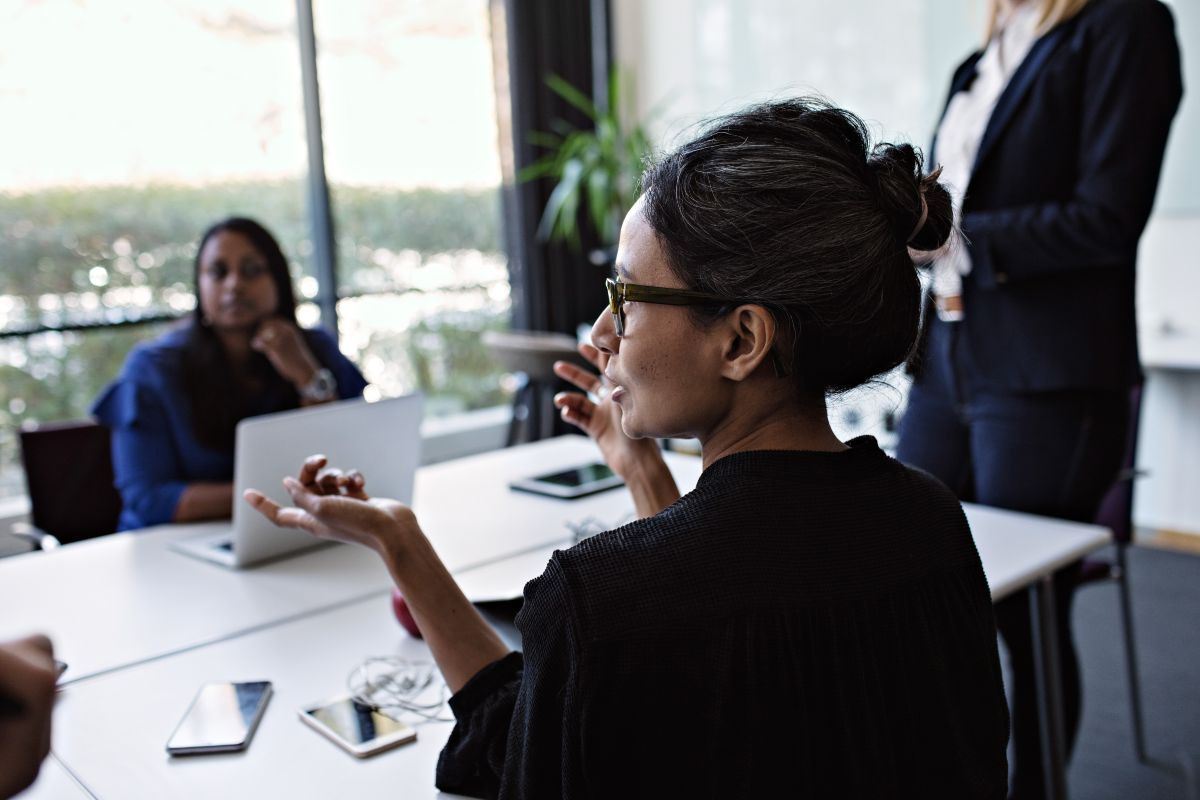 Business person talking to group at meeting room desk