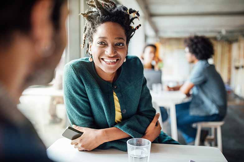 woman sitting at a desk smiling at person speaking