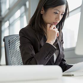 woman sitting at desk looking down at paper in hand