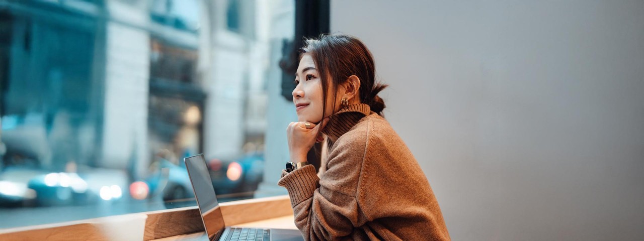 woman at work looking pensive at desk with laptop