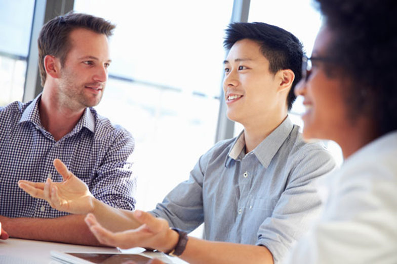 man sitting with two colleagues and gesturing while chatting