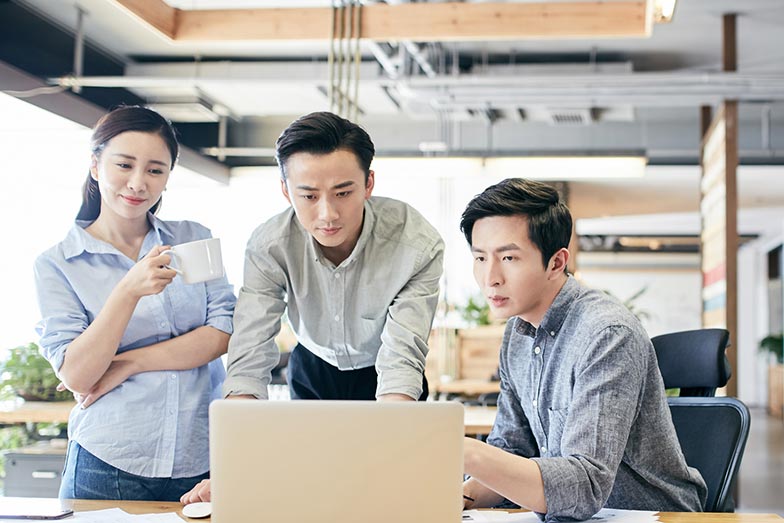 three office colleagues looking at a laptop