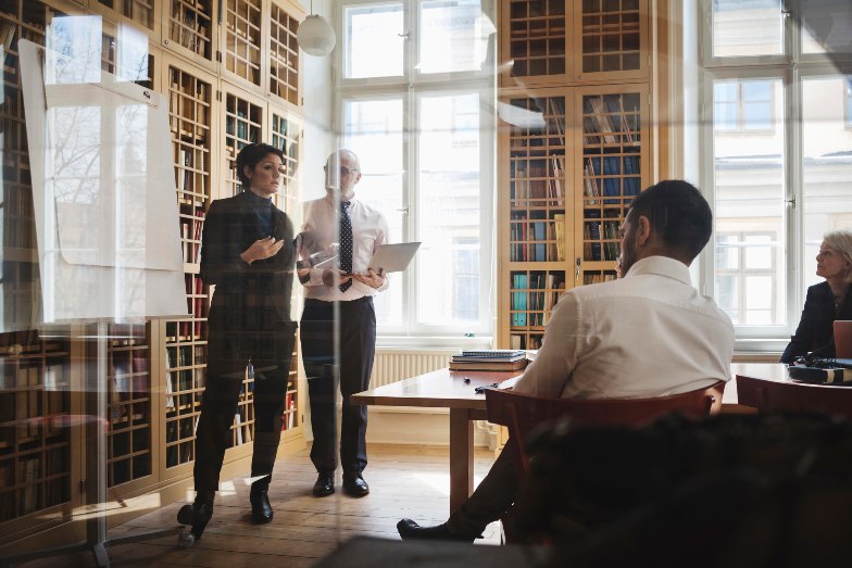 business person presenting to colleagues in office library