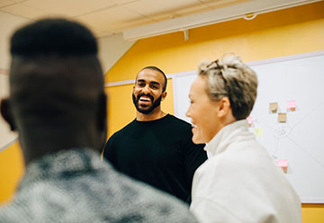 person in classroom laughing with two others