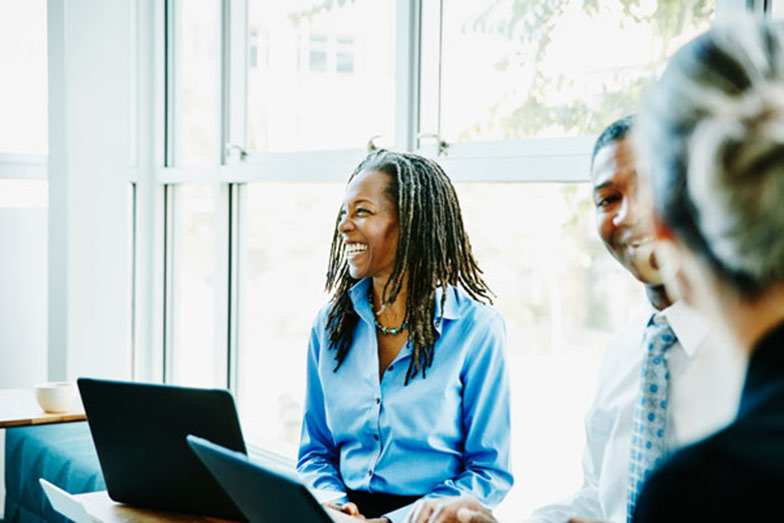 woman in business attire sitting with laptop and smiling