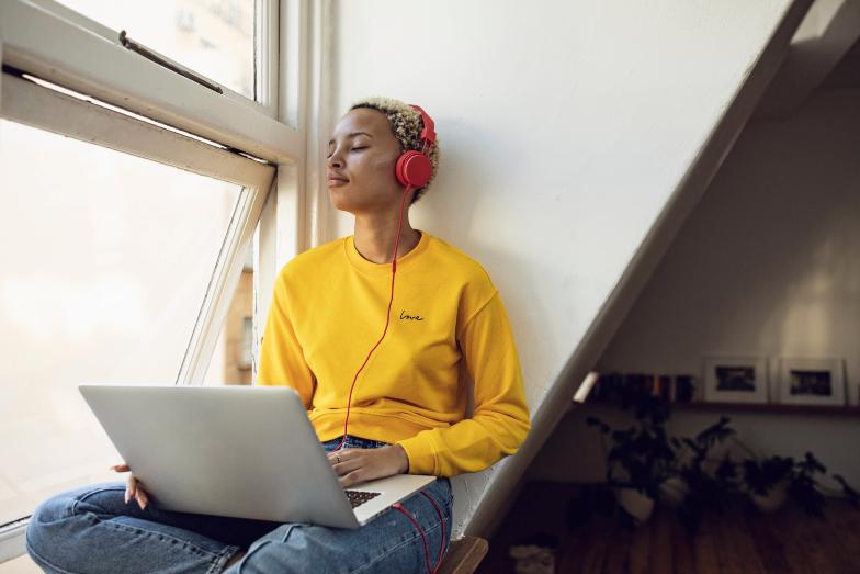 young person studying with laptop on window seat