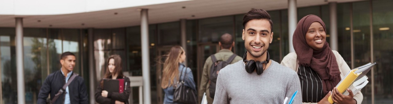 young people carrying books leaving building